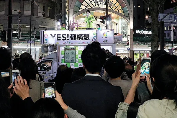街宣車の上でマイクを握る吉村代表代行＝当時＝の演説に耳を傾ける聴衆。大阪市北区