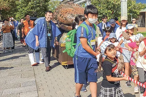 オオサンショウウオの巨大模型を冠した山車を曳（ひ）いて京都水族館の周りを一周する地元の子供達
